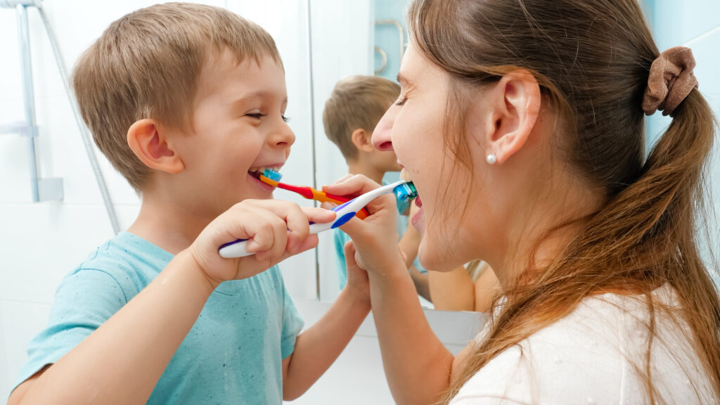 Mother and toddler having fun brushing teeth. 