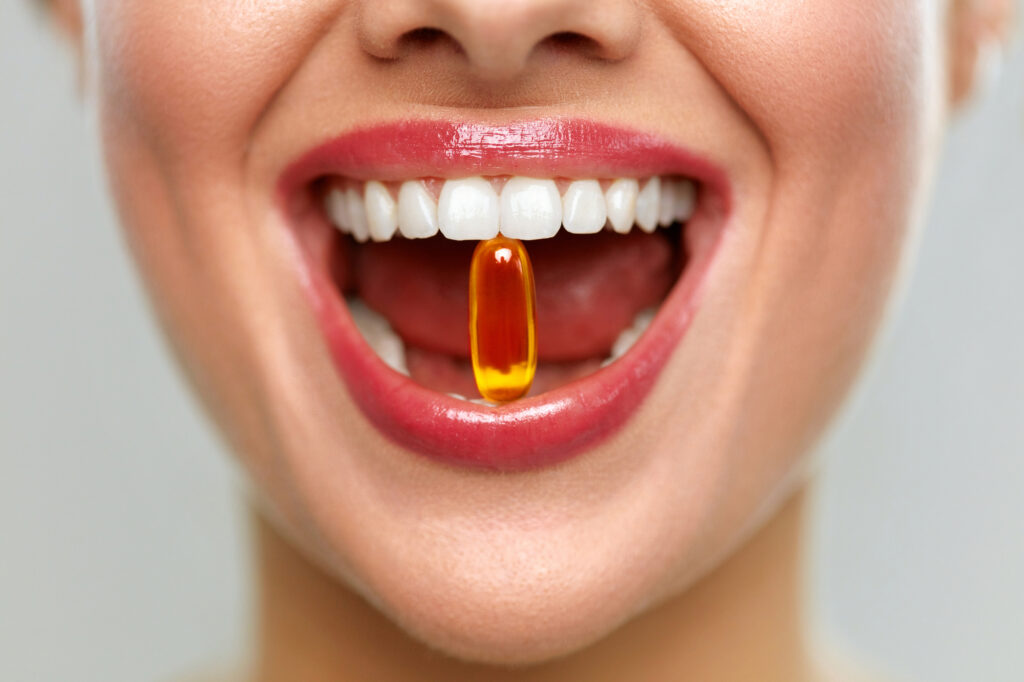 Woman with healthy teeth taking a vitamin suppliment. 