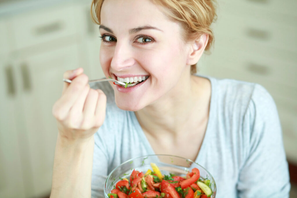 Woman with a white smile eating a healthy salad.