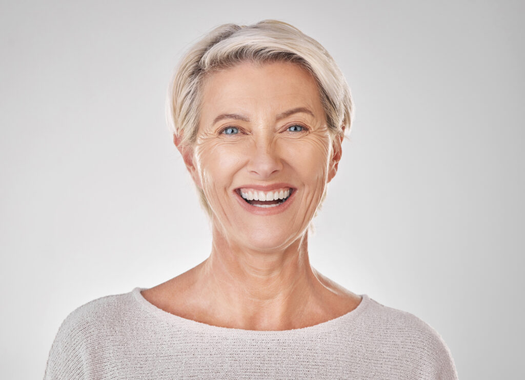 Senior woman showing off strong, beautiful modern dentures. 