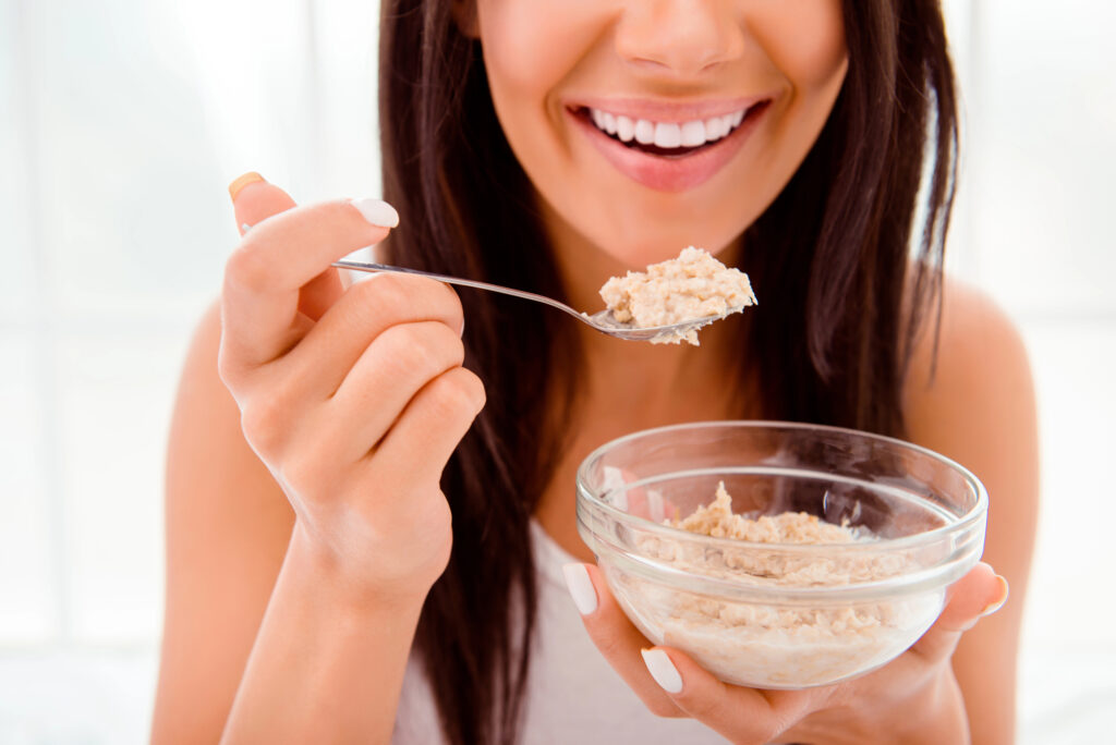 Woman with healthy white teeth eating breakfast. 