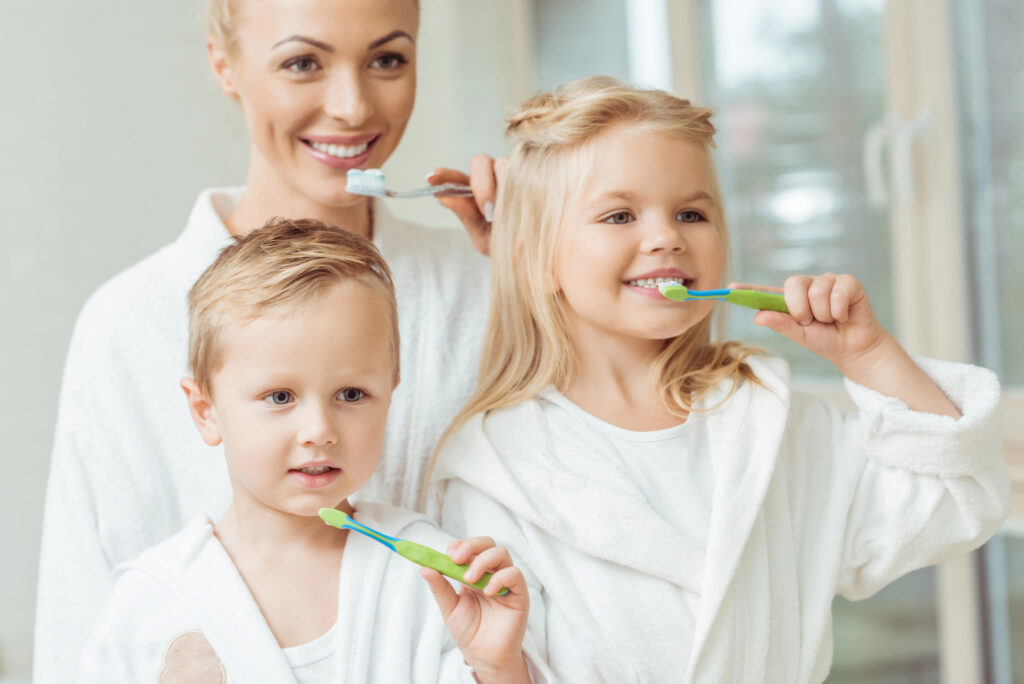 Mom and kids brushing teeth. 