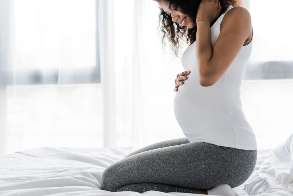 Pregnant woman smiling on bed. 